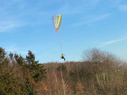 RC Gleitschirm fliegt vor einem Wald im Herbst