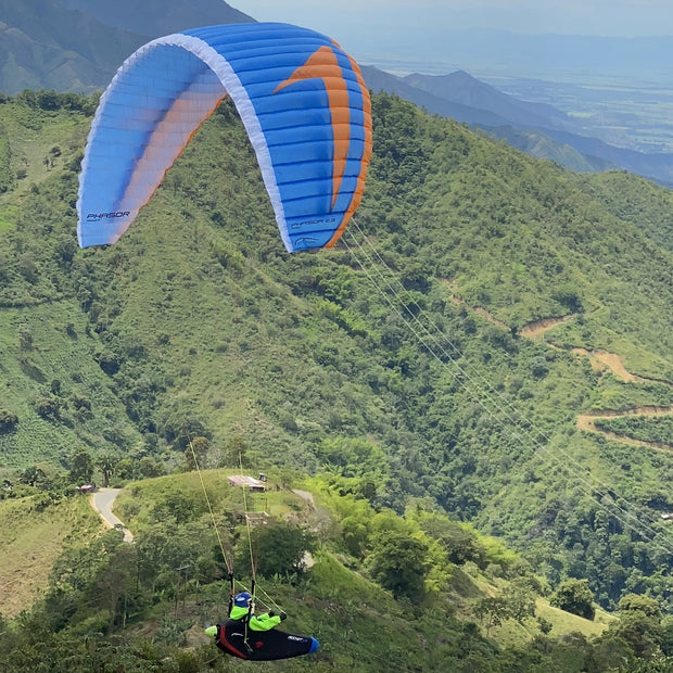 RC Gleitschirm in blau mit Liegegurtzeug Rock fliegt durch ein bewaldetes Thal t