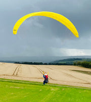 rc Paraglider in gelb über Kornfeld. Im Hintergrund regen